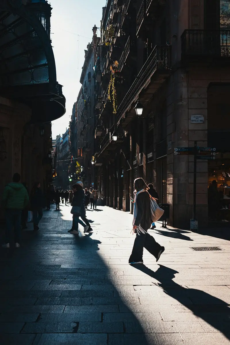 Pedestrians walking through a sunlit street in Barcelona