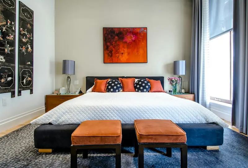 Illustrative bedroom with a large bed, colourful cushions and daylight