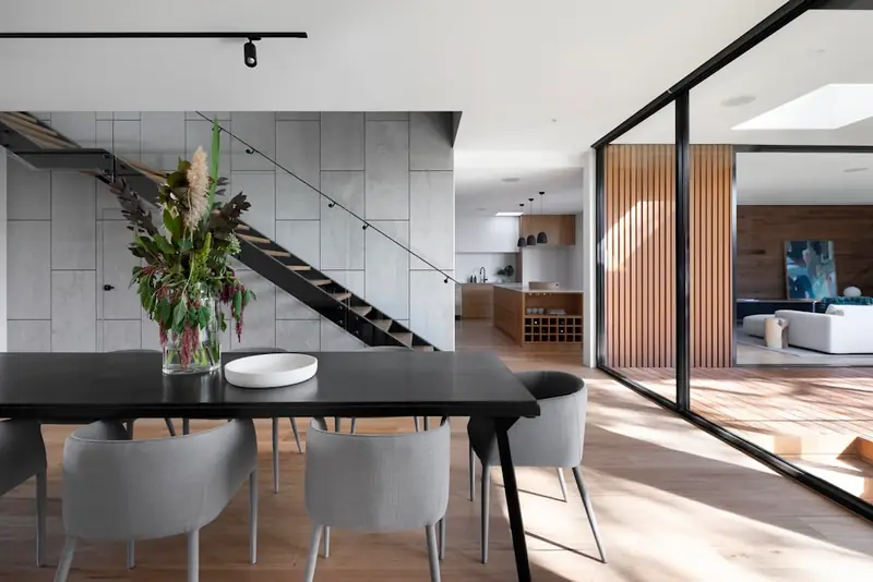 Illustrative dining table and chairs beside an open staircase