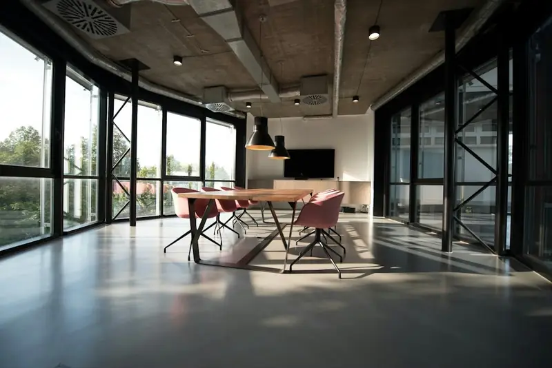 Illustrative communal work table beside large windows